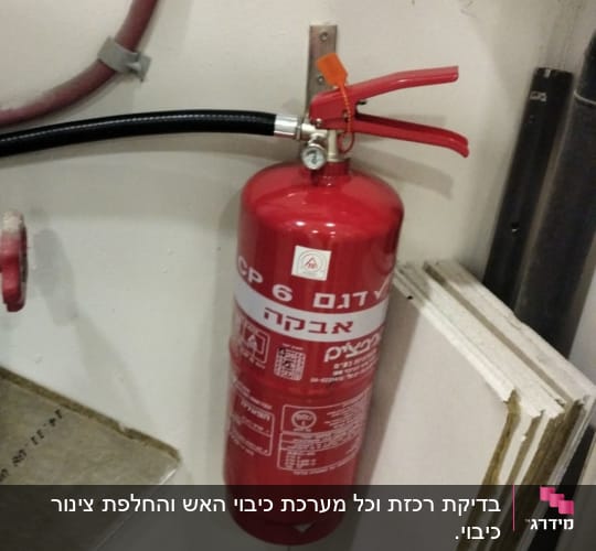 מטף כיבוי אש מותקן על קיר עם צינור